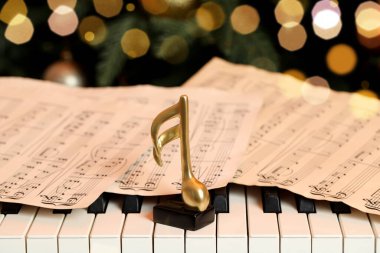 Noel ağacının yanındaki piyanoda altın nota ve çarşaflar, yakın plan. Bokeh etkisi
