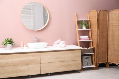 Ayna, damar lavabosu ve ev bitkileriyle süslü bir banyo.