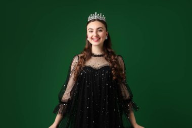 Yeşil arka planda lüks bir taç giyen mutlu kadın.