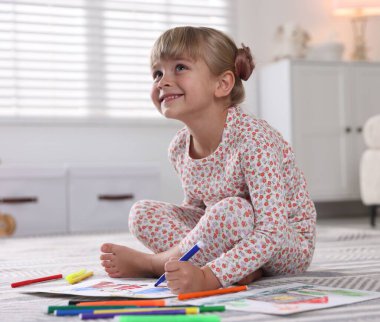 Evinde keçeli kalemle çizen sevimli küçük kız.