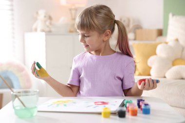 Beyaz masalarda avuç içleri çizen sevimli küçük kız.