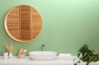 Ayna, damar lavabosu ve bitki örtüsü olan şık bir banyo.