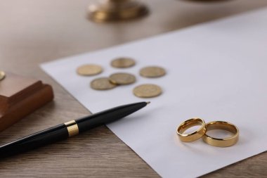 Nafaka. Alyanslar, kalem, madeni paralar ve belgeler ahşap masada, yakın plan.