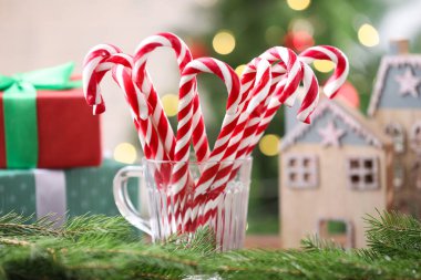 Bardaktaki şeker kamışları ve masadaki bulanık ışıklara karşı Noel süsü