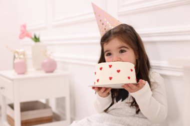 Doğum günü kutlaması. Parti şapkalı şirin küçük kız içeride lezzetli pastalar yiyor, mesaj atmak için yer var.