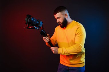 Kamerada çekim yapan kameraman, koyu arkaplandaki renk ışıklarına karşı titreşim dengeleyici kullanıyor.