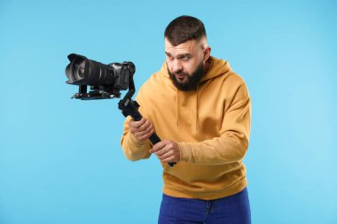 Açık mavi arkaplanda kameralı titreşim dengeleyici kullanan kameraman