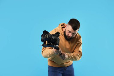 Kameraman açık mavi arkaplanda kameralı titreşimli dengeleyici kullanıyor. Metin için boşluk