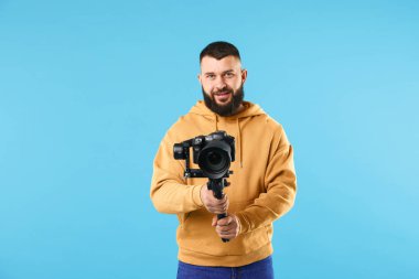 Açık mavi arkaplanda kameralı titreşim dengeleyici kullanan kameraman