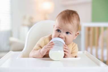 Evinde şezlongda yemek şişesi olan sevimli bir bebek. Metin için boşluk