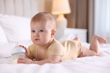Evde yatağında biberonla beslenen tatlı bir bebek. Metin için boşluk