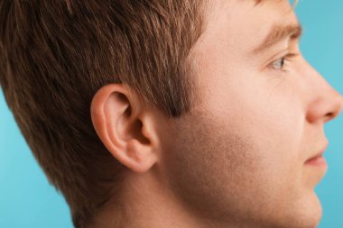 Ses geliyor. Açık mavi arka plandaki adam, yakın plan.