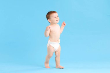 İlk adımlar. Açık mavi arka planda yürüyen şirin küçük bebek, metin için boşluk