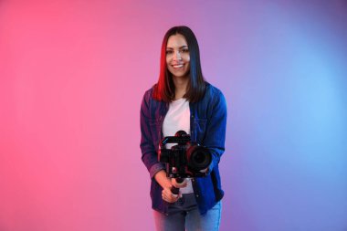 Kamerada çekim yapan kameraman, arka planda renk ışıklarıyla titreşim dengeleyici kullanıyor. Metin için boşluk