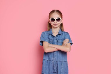 Pembe arka planda güneş gözlüklü tatlı bir kız.