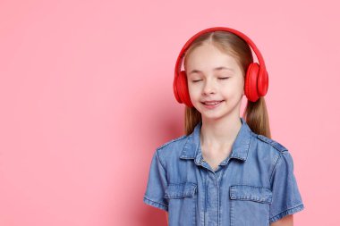 Pembe arka planda kulaklıklı tatlı kız, mesaj için yer var.