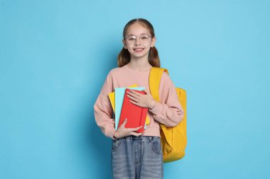 Sırt çantası ve açık mavi arka plan kitapları olan hoş bir kız.