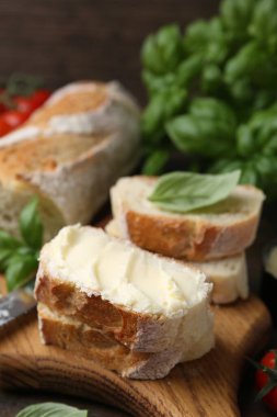 Tahta masada tereyağlı, fesleğenli ve bıçaklı baget dilimleri, yakın plan.