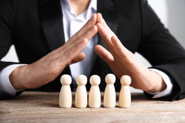 Ahşap masada insan figürlerini koruyan adam, yakın plan.