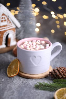 Gri masada lokum ve Noel dekoru olan lezzetli kakao bulanık ışıklara karşı, yakın plan.