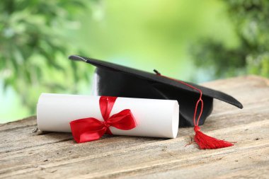Mezuniyet şapkası ve diploması ahşap masanın üzerinde bulanık arka plan, yakın plan