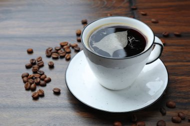 Aromatik kahve fincanda, fasulye de ahşap masada, yakın plan. Metin için boşluk