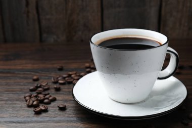 Aromatik kahve fincanda, fasulye de ahşap masada, yakın plan. Metin için boşluk