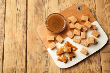 Ahşap masada tuz ve karamel soslu lezzetli şekerler. Metin için boşluk