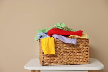 İçerideki bej duvarın yanındaki beyaz masada çamaşır sepeti, mesaj için yer var.