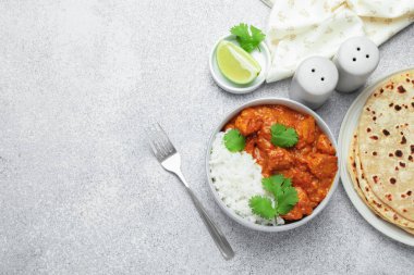 Pirinç, kişniş, kireç ve baharatlı leziz tavuk tikka masala. Gri desenli masa, düz yatak. Metin için boşluk
