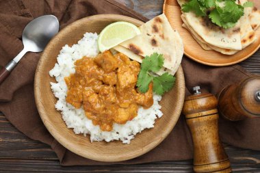 Pirinçli tavuk tikka masala, kişniş, kireç ve lavaş ahşap masada servis edilir.