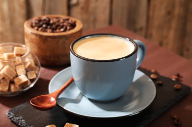 Kahve fincanda, fasulye ve esmer şeker masada, yakın plan.