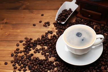 Aromatik kahve fincanda, fasulye ve öğütücü ahşap masada, yakın plan. Metin için boşluk