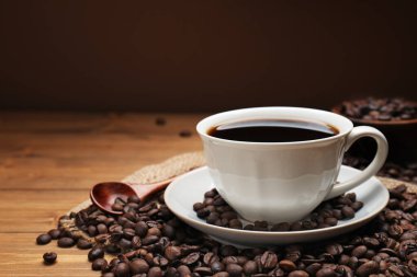 Aromatik kahve fincanda, fasulye de ahşap masada, yakın plan. Metin için boşluk