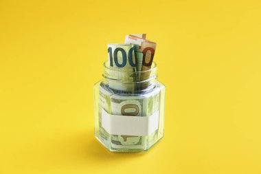 Boş notlu kavanoz ve sarı arka planda para