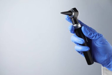 Açık gri arkaplanlı otoskoplu doktor, yakın plan. Metin için boşluk