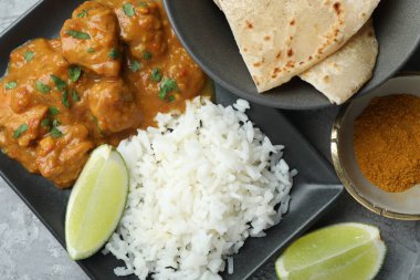 Gri desenli masada servis edilen pilavlı tavuk tikka masala.