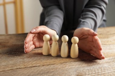 Ahşap masada insan figürlerini koruyan kadın, yakın plan.