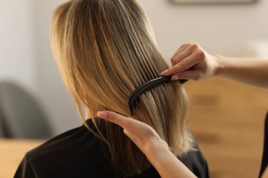 Kuaför kuaförde kadının saçını tarıyor, yakın plan.