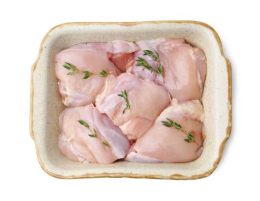 Çiğ tavuk butları ve kekik kabı beyaz, üst görünümde izole edilmiş.