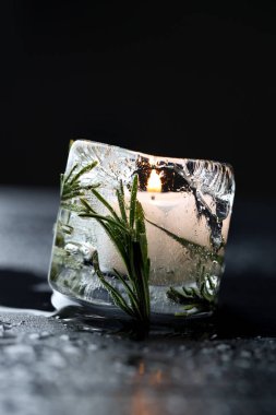 DIY Noel fenerleri. Siyah ahşap masada biberiyeli yanan buz mumu, yakın plan.