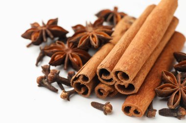Sıcak şarap baharatları. Tarçın çubukları, anason yıldızları ve karanfiller beyaz ahşap masada, yakın plan