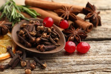 Farklı baharatlar, kızılcıklar, taze biberiye ve ahşap masada sıcak şarap için kuru portakal dilimi, yakın plan.