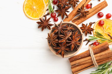 Farklı baharatlar, kuru portakal dilimleri, kızılcık ve taze biberiye beyaz ahşap masa üzerinde sıcak şarap, düz yatak. Metin için boşluk