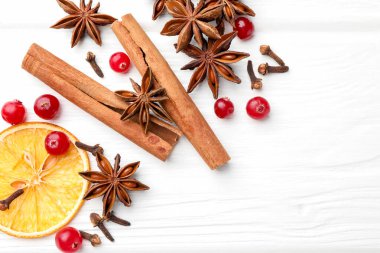 Farklı baharatlar, kuru portakal dilimleri ve beyaz ahşap masada sıcak şarap için kızılcıklar. Metin için boşluk