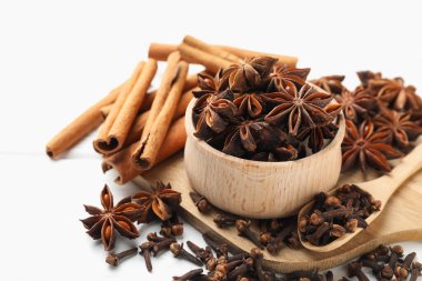 Sıcak şarap baharatları. Anise yıldızları kasede, tarçın çubukları ve karanfiller beyaz masada, yakın plan