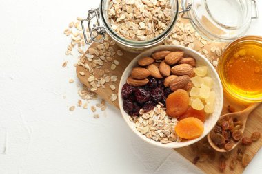 Tahıl yapıyorum. Yulaf gevreği, kurutulmuş meyve ve diğer malzemeler beyaz masada, düz yerde. Metin için boşluk