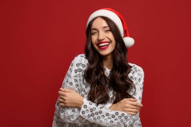 Kırmızı arka planda Noel Baba şapkalı güzel bir kadın. Noel sezonu