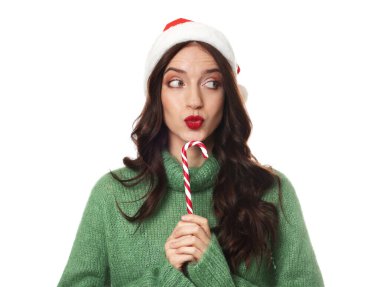 Beyaz arka planda Noel Baba şapkalı ve bastonlu güzel bir kadın. Noel sezonu