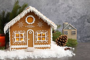 Gri masadaki güzel zencefilli kurabiye evi ve Noel dekoru, yakın plan.